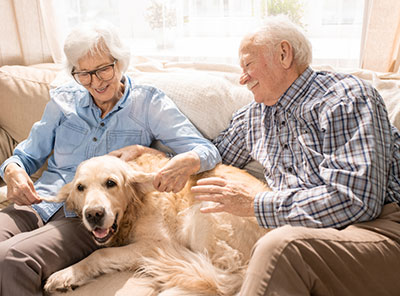 elderly couple petting their dog in memory care